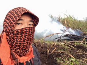 Photographer Baron Sekiya wearing a shemagh to filter out the smoke and ash on Maui at a cane fire.